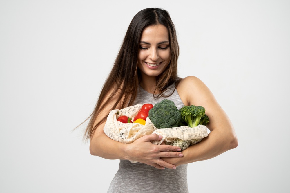 mujer feliz sostoene bolsa con hortalizas